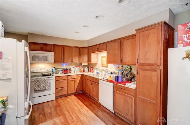 kitchen featuring a textured ceiling, light hardwood / wood-style floors, and white appliances