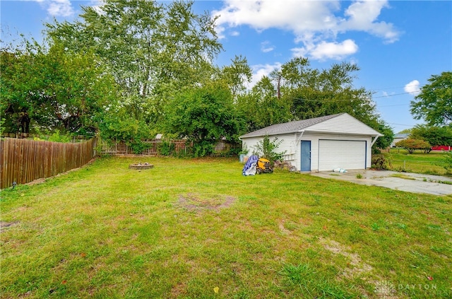 view of yard featuring a fire pit, an outdoor structure, and a garage