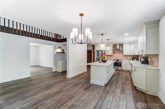 kitchen with sink, decorative light fixtures, wall chimney range hood, stainless steel appliances, and a center island