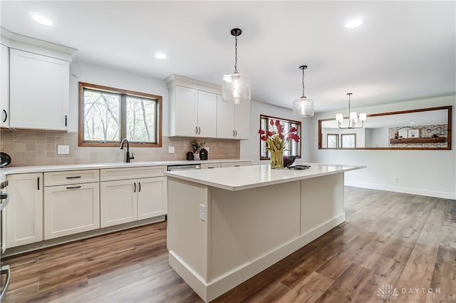 kitchen featuring pendant lighting, a kitchen island, sink, dark hardwood / wood-style floors, and white cabinets