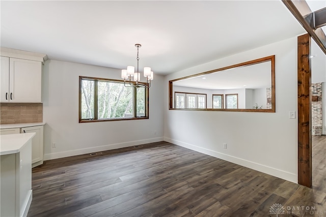 unfurnished dining area with an inviting chandelier and dark hardwood / wood-style flooring