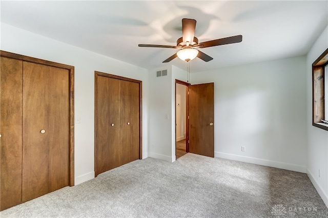 unfurnished bedroom with ceiling fan, carpet floors, and multiple closets