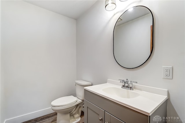 bathroom with wood-type flooring, vanity, and toilet