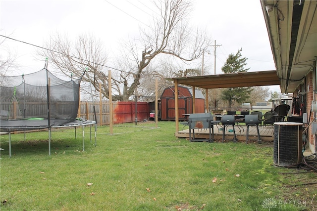 view of yard with a trampoline, a shed, and central air condition unit