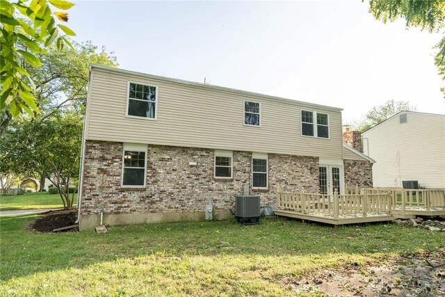 back of house with central AC, a wooden deck, and a lawn