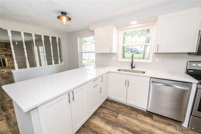 kitchen with stainless steel appliances, white cabinetry, sink, and kitchen peninsula