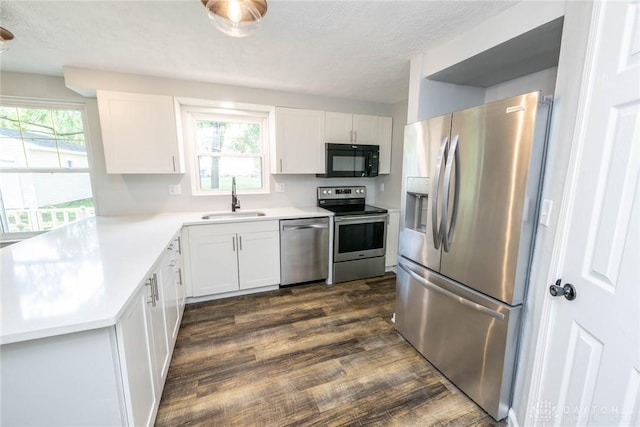 kitchen with white cabinets, stainless steel appliances, a textured ceiling, and sink