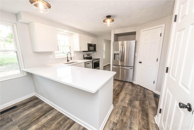 kitchen featuring kitchen peninsula, stainless steel appliances, white cabinets, and a healthy amount of sunlight