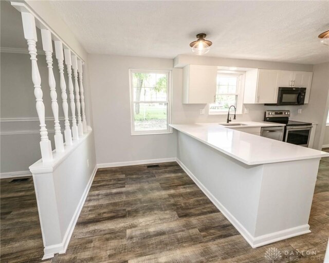 kitchen featuring stainless steel electric stove, sink, white cabinetry, a textured ceiling, and kitchen peninsula