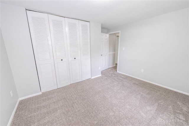 unfurnished bedroom featuring a closet and light carpet