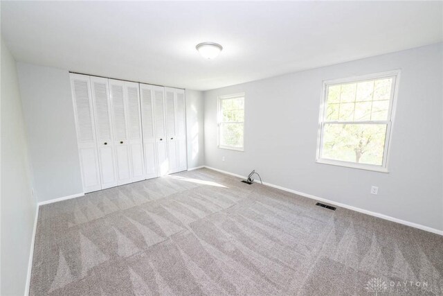 unfurnished bedroom featuring a closet and light colored carpet