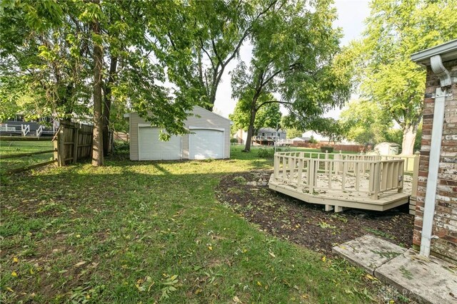 view of yard with a garage, a deck, and an outbuilding