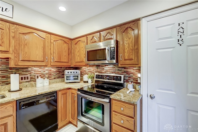 kitchen with light stone counters, appliances with stainless steel finishes, backsplash, and light tile patterned floors