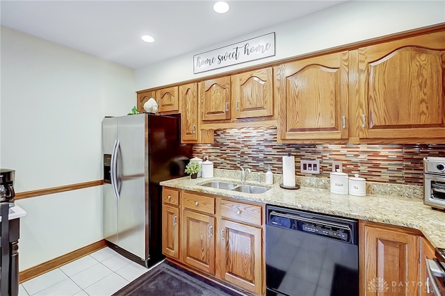 kitchen with stainless steel fridge, tasteful backsplash, black dishwasher, light stone countertops, and sink