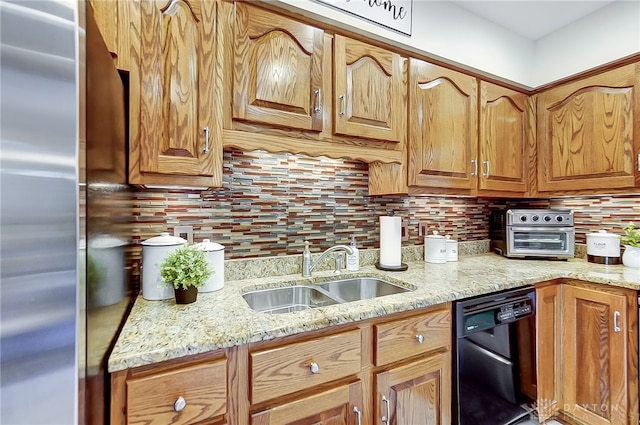 kitchen featuring black dishwasher, stainless steel refrigerator, light stone counters, and sink