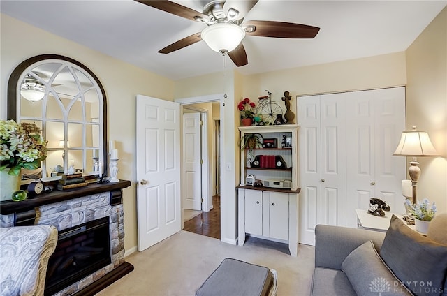 living room featuring ceiling fan, light colored carpet, and a fireplace