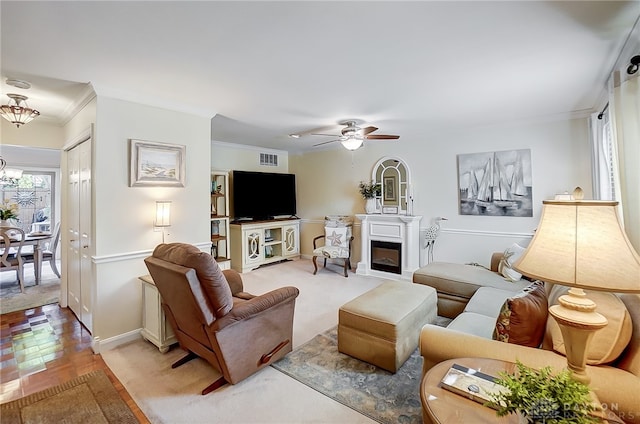 living room with ornamental molding, parquet flooring, and ceiling fan with notable chandelier