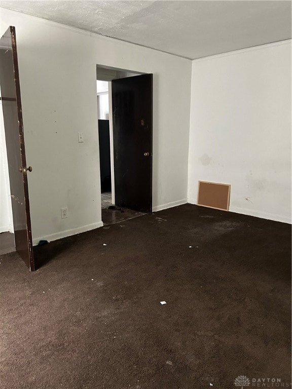 spare room with a textured ceiling and dark colored carpet