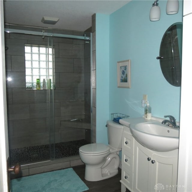 bathroom featuring vanity, toilet, and a shower with shower door