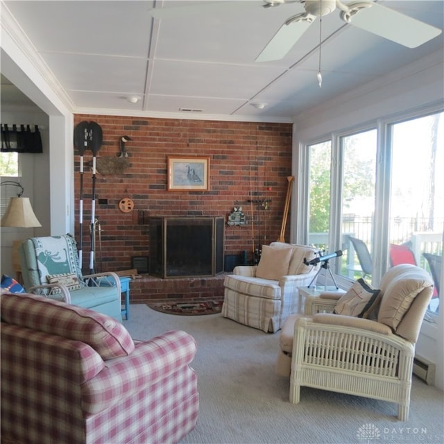 carpeted living room with a brick fireplace, crown molding, brick wall, and ceiling fan