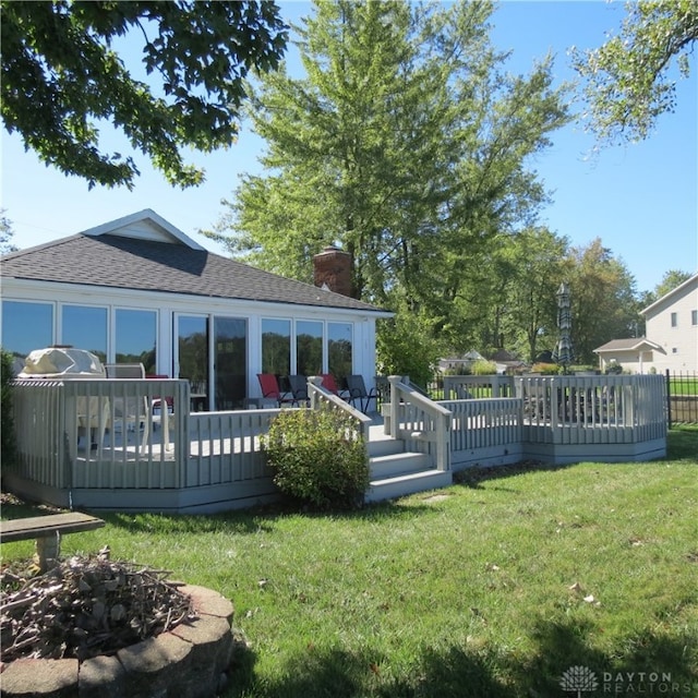 rear view of property with a deck and a yard