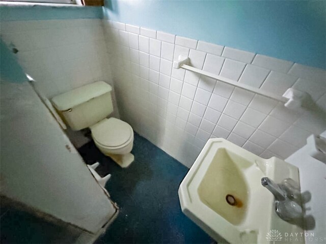 bathroom featuring tile walls and toilet