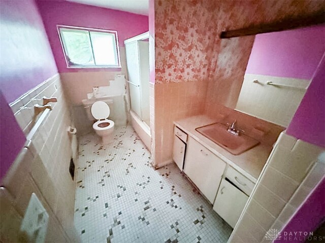 bathroom with tile walls, vanity, tile patterned flooring, toilet, and an enclosed shower