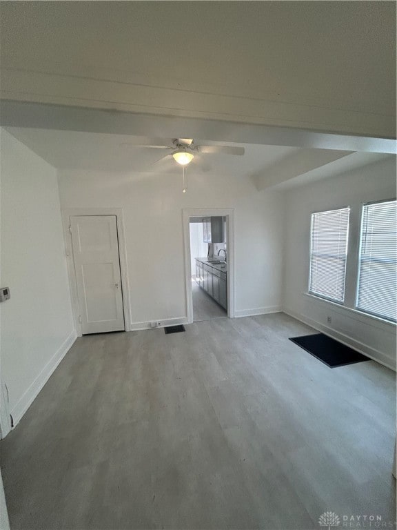 unfurnished room featuring ceiling fan, beam ceiling, and light hardwood / wood-style floors