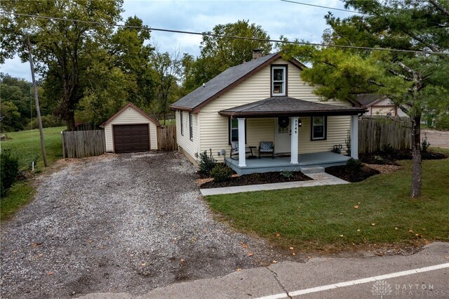 view of front of property featuring a porch, a garage, a front lawn, and an outdoor structure