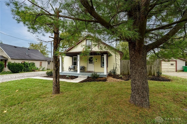 view of front facade featuring an outbuilding, a garage, covered porch, and a front yard