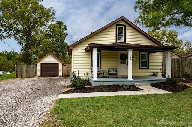 bungalow-style home featuring a garage, an outdoor structure, a front lawn, and covered porch