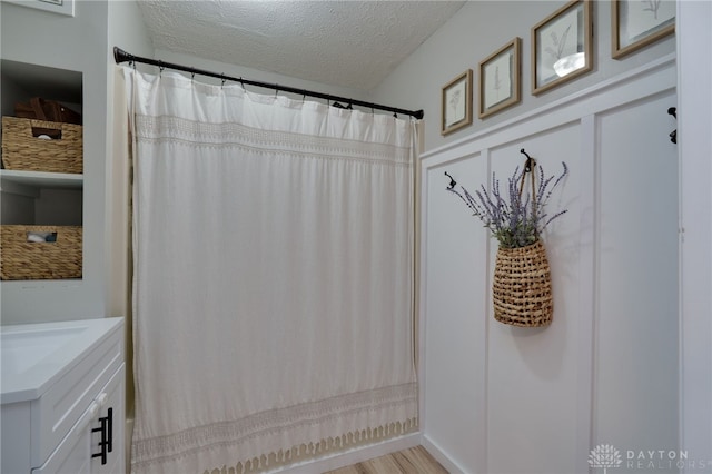 bathroom with walk in shower, vanity, a textured ceiling, and hardwood / wood-style flooring