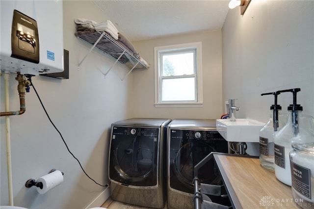 washroom with a textured ceiling, tankless water heater, and washing machine and clothes dryer