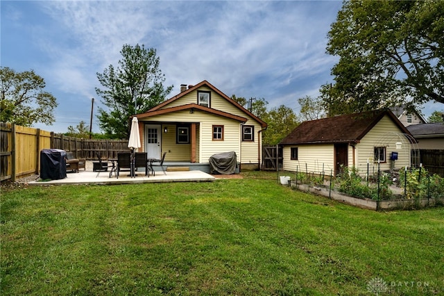 back of house featuring a yard, an outbuilding, and a patio area