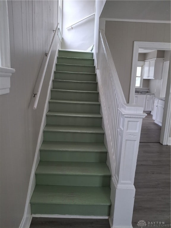 stairway with wood-type flooring and wooden walls