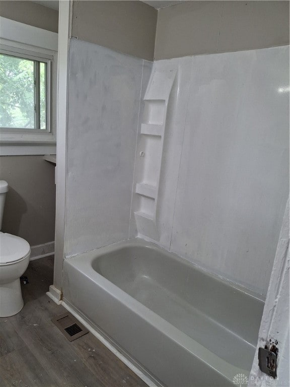 bathroom featuring shower / bathtub combination, hardwood / wood-style floors, and toilet