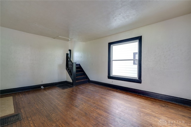 empty room featuring a textured ceiling and dark hardwood / wood-style floors