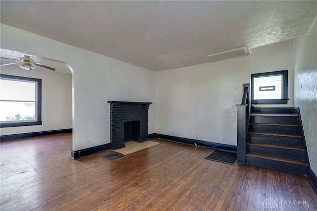 unfurnished living room featuring a textured ceiling, a fireplace, dark hardwood / wood-style floors, and a wealth of natural light