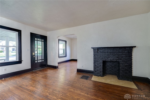 unfurnished living room with a fireplace and dark wood-type flooring