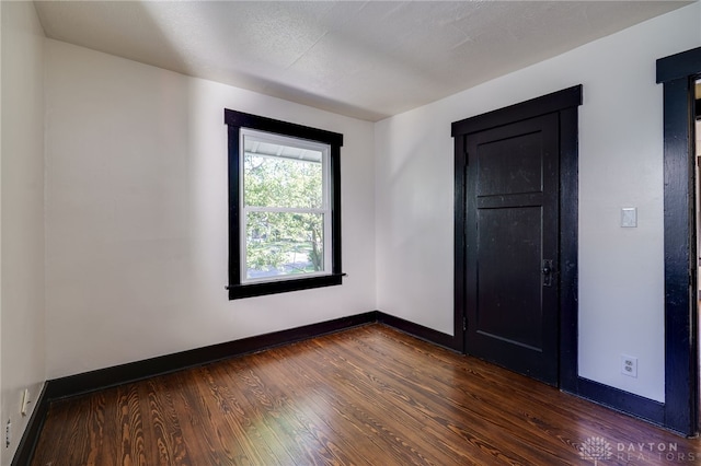 unfurnished room with dark wood-type flooring