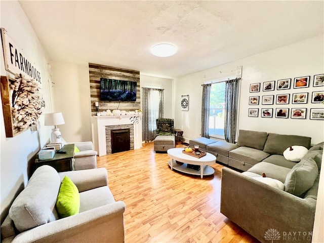 living room featuring wood-type flooring and a stone fireplace