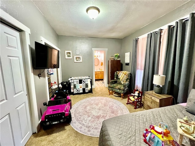 bedroom with a textured ceiling, ensuite bathroom, and light colored carpet