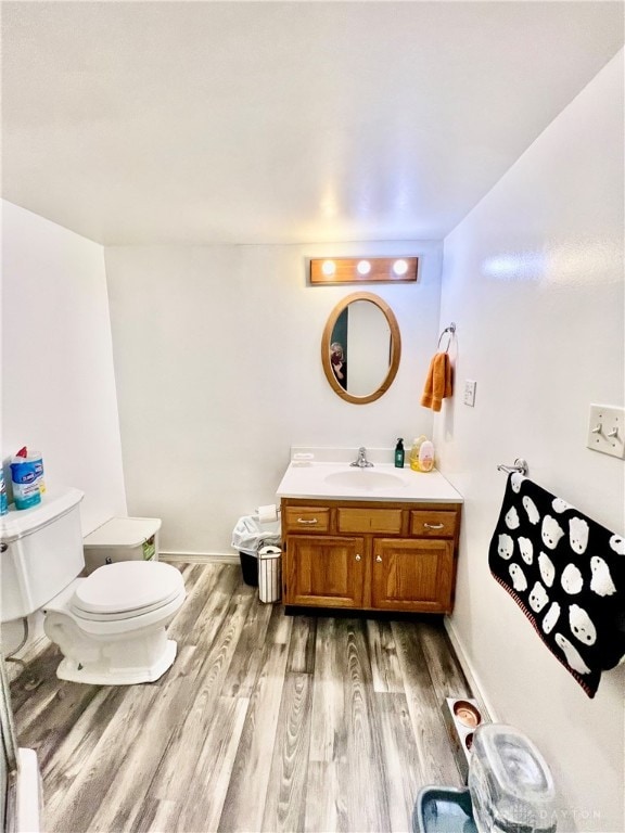 bathroom with wood-type flooring, vanity, and toilet