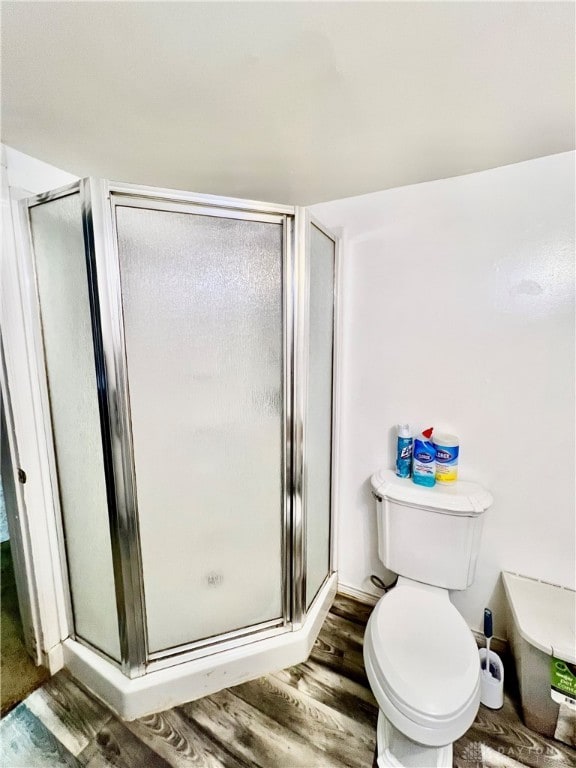 bathroom with wood-type flooring, an enclosed shower, and toilet