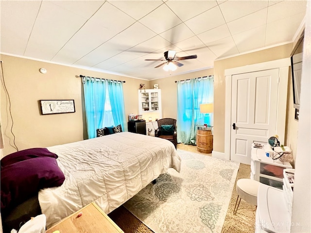 carpeted bedroom with ornamental molding and ceiling fan