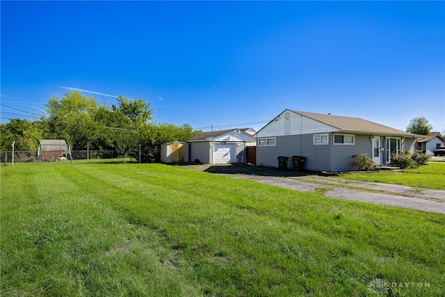 view of yard with driveway, a detached garage, an outdoor structure, and fence