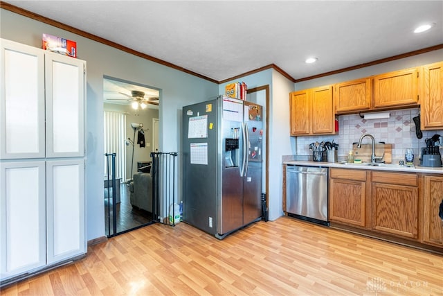 kitchen with stainless steel appliances, light wood-style floors, light countertops, decorative backsplash, and a sink