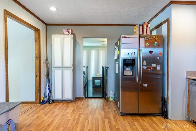 kitchen featuring ornamental molding, light wood-type flooring, a textured ceiling, and appliances with stainless steel finishes