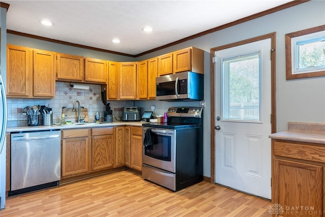 kitchen featuring appliances with stainless steel finishes, decorative backsplash, sink, light wood-type flooring, and ornamental molding