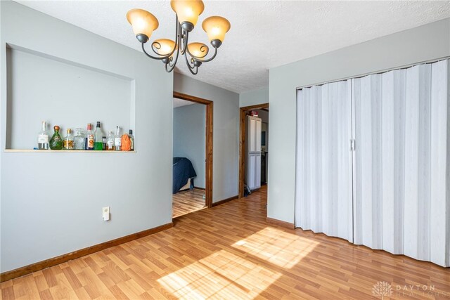 unfurnished dining area with hardwood / wood-style floors, an inviting chandelier, and a textured ceiling